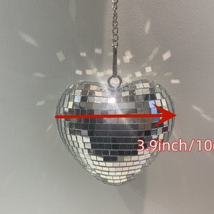 Peut inclure: Une boule disco en forme de cœur argentée avec une chaîne suspendue au sommet. La boule mesure 3,9 pouces de large.