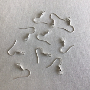 May include: A collection of eight silver-toned metal earring hooks, each featuring a curved wire, a small decorative bead, and a loop at the bottom for attaching jewelry components. These findings are designed for crafting earrings.