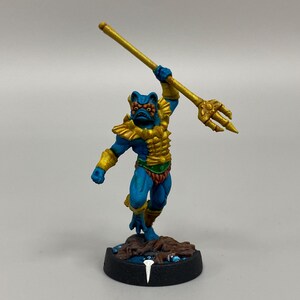 Miniatura de tritón pintada y tarjetas de juego para el juego Masters of the Universe Battleground, de Archon Studio.