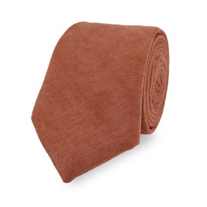 May include: A solid rust-coloured tie made of a textured fabric.