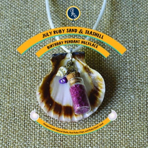 May include: A pendant necklace featuring a seashell with a small glass vial filled with ruby-colored sand. The necklace includes the text "JULY RUBY SAND & SEASHELL BIRTHDAY PENDANT NECKLACE". The design incorporates natural shells and ruby chips.