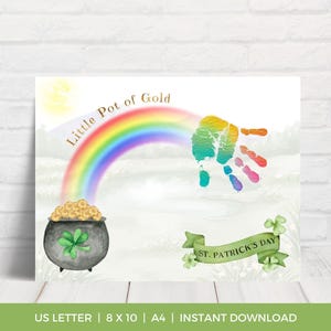 May include: A St. Patrick's Day themed print featuring a rainbow arching over a pot of gold. A colorful handprint is above the rainbow. The words "Little Pot of Gold" are above the rainbow. A green banner reads "St. Patrick's Day".