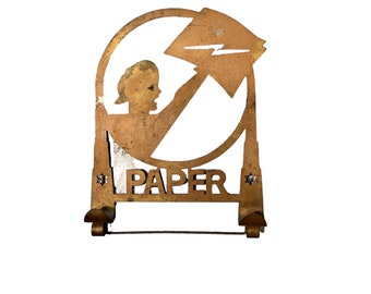 May include: A gold metal paper holder with a silhouette of a person holding a piece of paper. The holder has the word "PAPER" written on it.