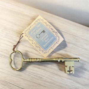 May include: A gold-toned metal key with a heart-shaped bow and a decorative keyhole. The key is labeled "James River Collection, Authentic Colonial Brass Reproductions, Forged by Baldwin".