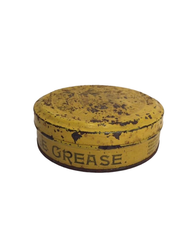 Puede incluir: Una lata de metal amarilla con las palabras "Grease" impresas en el lateral. La lata es vieja y tiene algo de &oacute;xido.