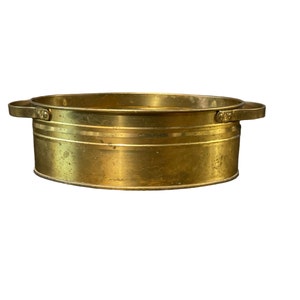 May include: A brass oval serving dish with two handles. The dish has a hammered finish and a slightly distressed look.