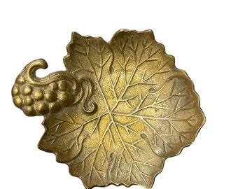 May include: A brass trinket dish shaped like a grapevine leaf with a grape cluster handle.