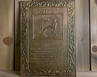 Puede incluir: Placa rectangular de latón con la palabra "MOTHER" en la parte superior. La placa presenta un bajorrelieve de una figura sentada y un poema sobre la maternidad. El marco tiene un diseño floral ornamentado.