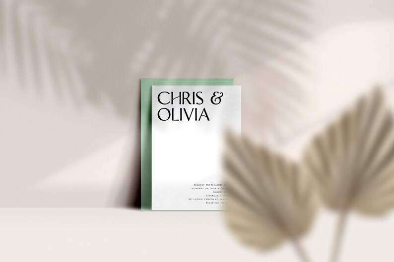 May include: A wedding invitation featuring the names "Chris & Olivia" in elegant black font. The invitation is on a white background, set against a pale green backing. The design includes additional text and is set against a neutral background with a shadow.