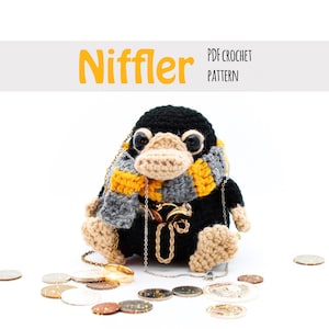 May include: A black and brown crocheted Niffler toy from the Harry Potter series, holding a variety of gold coins and jewellery. The Niffler is wearing a grey and yellow scarf. The text "Niffler PDF CROCHET PATTERN" is above the toy.