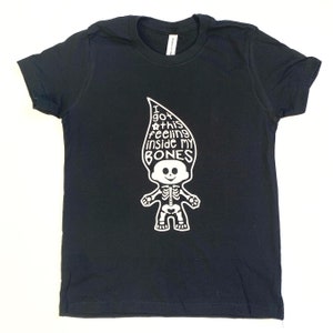 May include: A black short-sleeved t-shirt featuring a white graphic of a troll doll with a skeleton ribcage and pelvis. The troll's hair is shaped like a flame and contains the text: I GOT THIS feeling inside MY BONES, with a small flower icon.