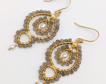May include: Gold-toned wire earrings with a unique, openwork design. The earrings feature gray gemstone beads and small white pearls. The intricate wirework forms a spiral and teardrop shape, creating an elegant and artistic look.