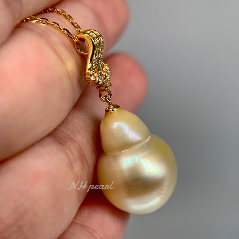 Puede incluir: Un collar de oro con un colgante de una gran perla barroca blanca nacarada. La perla est&aacute; unida a una cadena de oro con una peque&ntilde;a argolla engastada con diamantes.