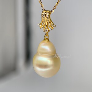 Puede incluir: Un collar de oro con un gran colgante de perla barroca blanca nacarada. El colgante est&aacute; unido a una delicada cadena de oro con un peque&ntilde;o dise&ntilde;o ornamentado de oro y cristal.