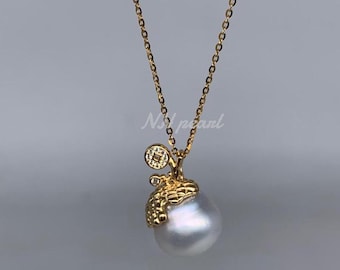 Könnte beinhalten: Eine goldene Kettenkette mit einem großen weißen Barockperlenanhänger. Die Perle ist in einem goldenen Filigranmuster mit einem kleinen Diamantenakzent gefasst.