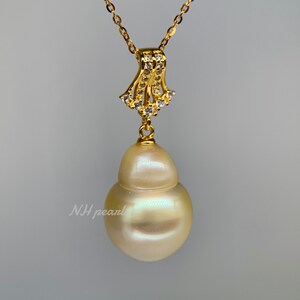 Puede incluir: Un collar de oro con un gran colgante de perla barroca blanca nacarada. El colgante est&aacute; unido a una delicada cadena de oro con un peque&ntilde;o colgante en forma de diamante.