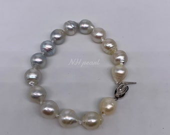 May include: A pearl bracelet with a silver clasp. The pearls are a mix of white and gray.