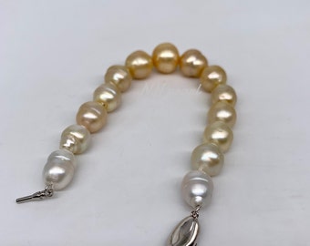 May include: A pearl bracelet with a gradient of white and gold pearls. The bracelet has a silver clasp.