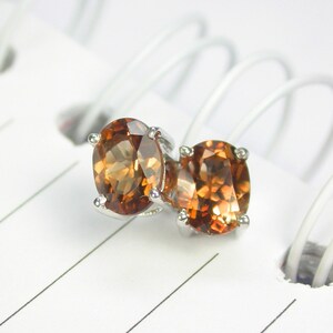 May include: A pair of silver stud earrings with round, faceted, brown gemstones.