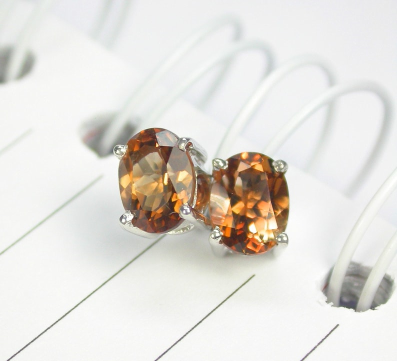 May include: A pair of silver stud earrings with round, faceted, brown gemstones.