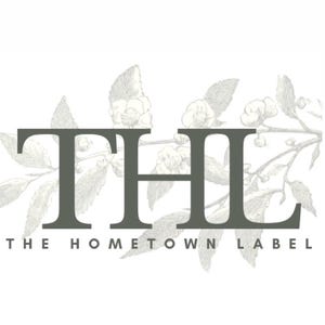 May include: Black and white illustration of a floral design with the text "THE HOMETOWN LABEL" and the letters "THL" in a large font.