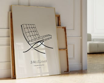 May include: A framed art print featuring a black line drawing of a Barcelona chair. The print has a gold frame and the word "BARCELONA" is written below the chair illustration. The print is leaning against a white wall.