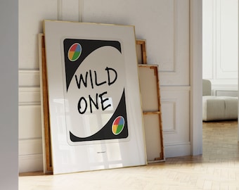 May include: A framed print of a black Uno card with the text "WILD ONE" in white. The card has four colored circles in the top left and bottom right corners.