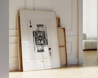 May include: A black and white illustration of the King of Spades playing card in a gold frame. The card is leaning against a white wall.
