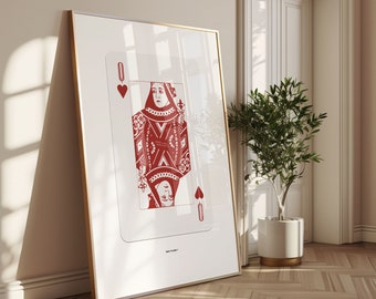 Op de afbeelding: Een rode Queen of Hearts speelkaart print in een gouden lijst. De kaart is een traditioneel ontwerp met een rode achtergrond en witte details. De Queen draagt een kroon en een lange jurk. De kaart is omgeven door een witte rand.