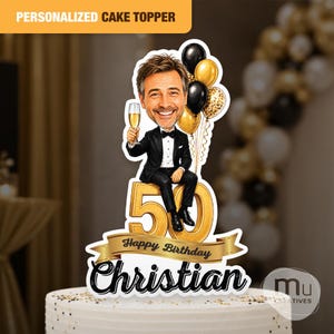 Op de afbeelding: Een gepersonaliseerde taarttopper met een cartoonillustratie van een man in een zwart smoking die een champagneglas vasthoudt, zittend op een groot goudkleurig cijfer 50. Achter hem zijn zwarte en gouden ballonnen. Een gouden banner toont Happy Birthday Christian.