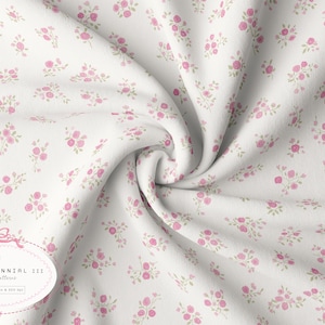 May include: White fabric featuring a delicate pattern of pink roses and green foliage. The fabric is arranged in soft folds, creating a textured appearance. The design is labelled "GRANDMILLENNIAL 111" with a bow illustration.