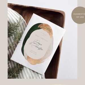 Puede incluir: Una tarjeta blanca con un dise&ntilde;o abstracto dorado y verde. La tarjeta dice "We wish you a very Merry Christmas & Happy New Year".