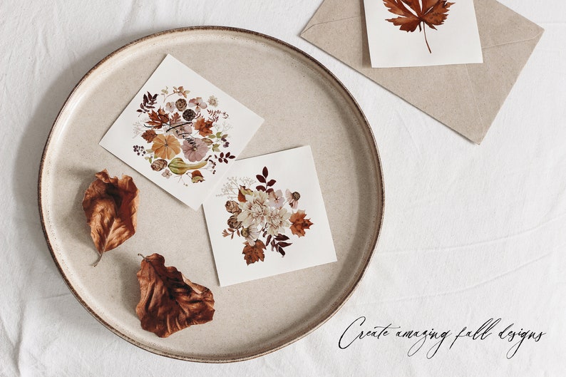Op de afbeelding: Twee kaarten met gedroogde bloemenontwerpen op een beige bord. De kaarten bevatten een verscheidenheid aan gedroogde bloemen en bladeren in tinten bruin, roze en wit. De tekst "Create amazing fall designs" is in cursief geschreven op het witte oppervlak onder het bord.