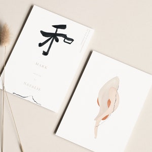 May include: Two minimalist wedding invitations with a black and white abstract design and the text "Mark & Natalie" on one card and a beige and orange abstract design on the other card.