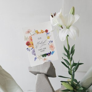 May include: A white card with a floral border and the text "You are invited" and "Michael & Jane Save the Date" in black lettering.