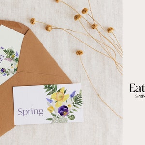 May include: Two cards with floral designs and the text "Wild" and "Spring" on a brown envelope. The envelope is on a white textured background with dried flowers.