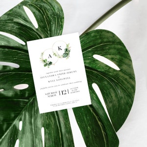 May include: A white wedding invitation with green foliage and gold rings with the initials A and K. The text reads "together with their parents Alexandra Smith & Jeremy Kyle Longwell joyfully invite you to celebrate their wedding Saturday March |12| 12 o'clock in the afternoon Tropical Gardens & Suites Tamarindo Costa Rica"