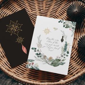 May include: A white card with a watercolor illustration of winter greenery and snowflakes. The text on the card reads "May the warm wishes of the new year reach you and your loved ones!"