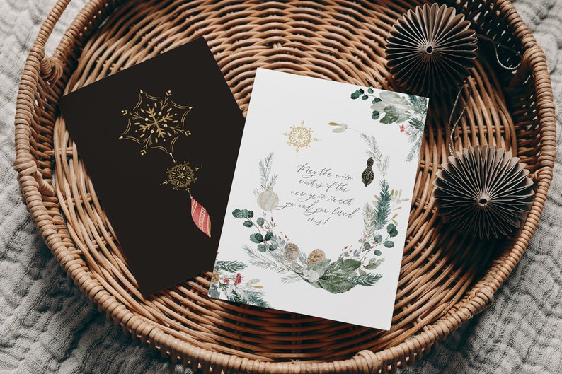 May include: A white card with a watercolor illustration of winter greenery and snowflakes. The text on the card reads "May the warm wishes of the new year reach you and your loved ones!"