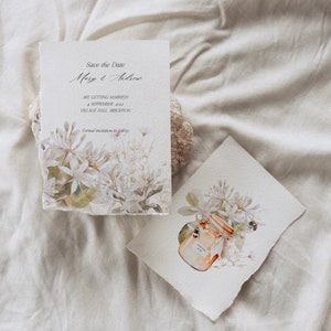 May include: Save the Date card with white flowers and green leaves. The text reads "Save the Date Mary & Andrew Are getting married 4 September 2022 Village Hall, Brighton Formal invitation to follow"