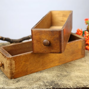 Peut inclure: Deux bo&icirc;tes en bois avec une finition teint&eacute;e brune. Les bo&icirc;tes sont empil&eacute;es l'une sur l'autre. La bo&icirc;te du haut est ouverte et la bo&icirc;te du bas est ferm&eacute;e. Les bo&icirc;tes ont un bouton sur le devant.
