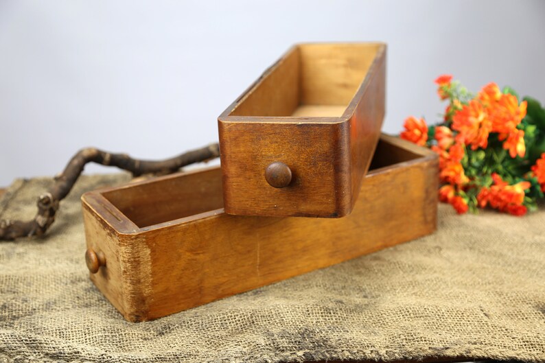 Peut inclure: Deux bo&icirc;tes en bois avec une finition teint&eacute;e brune. Les bo&icirc;tes sont empil&eacute;es l'une sur l'autre. La bo&icirc;te du haut est ouverte et la bo&icirc;te du bas est ferm&eacute;e. Les bo&icirc;tes ont un bouton sur le devant.
