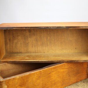Peut inclure: Une bo&icirc;te en bois avec un couvercle &agrave; charni&egrave;re. La bo&icirc;te est en bois brun clair et a une forme rectangulaire simple. La bo&icirc;te est ouverte et vide.