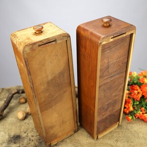 Peut inclure: Deux bo&icirc;tes en bois avec couvercles et un bouton sur le dessus. Les bo&icirc;tes sont faites de diff&eacute;rents types de bois et ont une finition naturelle. Les bo&icirc;tes sont pos&eacute;es sur une surface en toile de jute.