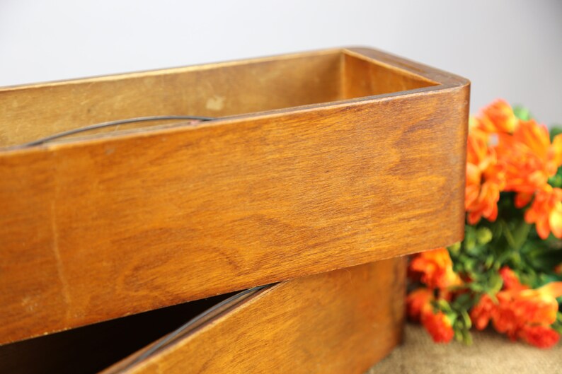 Peut inclure: Deux bo&icirc;tes rectangulaires en bois empil&eacute;es l'une sur l'autre. Les bo&icirc;tes sont en bois naturel avec une teinte brun clair. La bo&icirc;te du haut est vide et la bo&icirc;te du bas est partiellement visible.