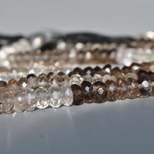 Peut inclure: Un collier de perles de quartz fumé facettées dans des tons de brun et clair. Les perles sont enfilées sur un cordon et ont un pompon à une extrémité.