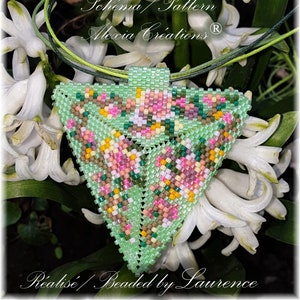Peut inclure: Un pendentif triangulaire en perles vertes, roses et brunes avec un motif floral. Le pendentif est suspendu à un cordon vert et est entouré de fleurs blanches.