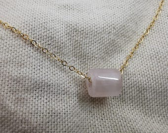Può includere: Una collana con catena dorata e un ciondolo cilindrico rosa chiaro.