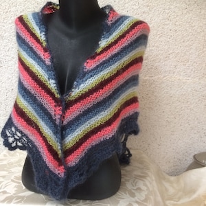 Può includere: Uno scialle a maglia a righe con un bordo all'uncinetto in tonalità di blu, rosa, verde e marrone.