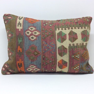 May include: A rectangular cushion with a colourful geometric pattern. The cushion is made of woven fabric and has a brown, red, blue, and white colour scheme.